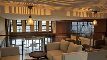 A modern interior with a glass railing, a sofa set, and pendant lighting.