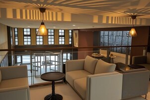 A modern interior with a glass railing, a sofa set, and pendant lighting.