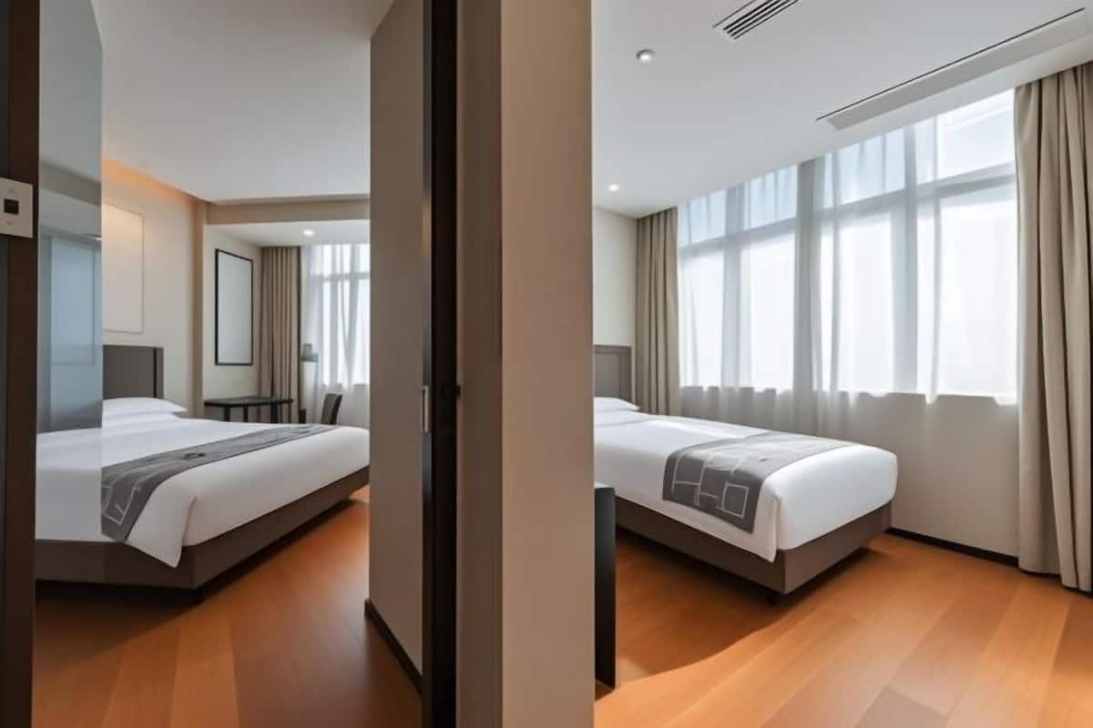 Una habitación de hotel moderna con una cama grande, un escritorio y una ventana con cortinas.