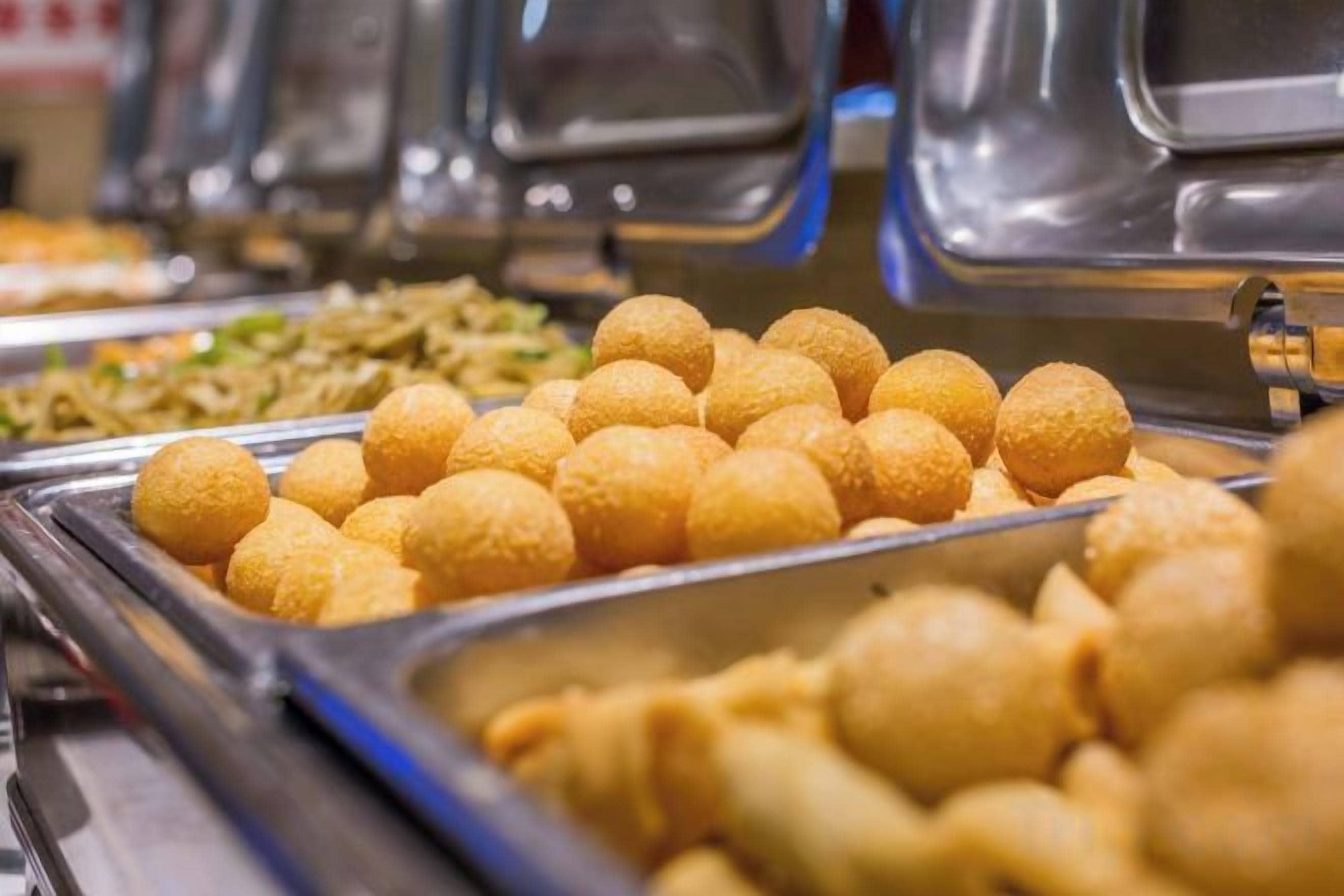 A buffet with various food items, including a tray of golden-brown fried balls.