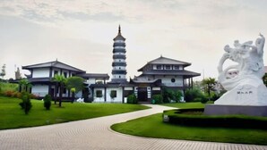 A traditional building with a pagoda-style tower, a large statue, and a well-maintained garden. - WGSY Hotel (Hefei Economic Development Zone Mingzhu Square University Town) (Hefei)