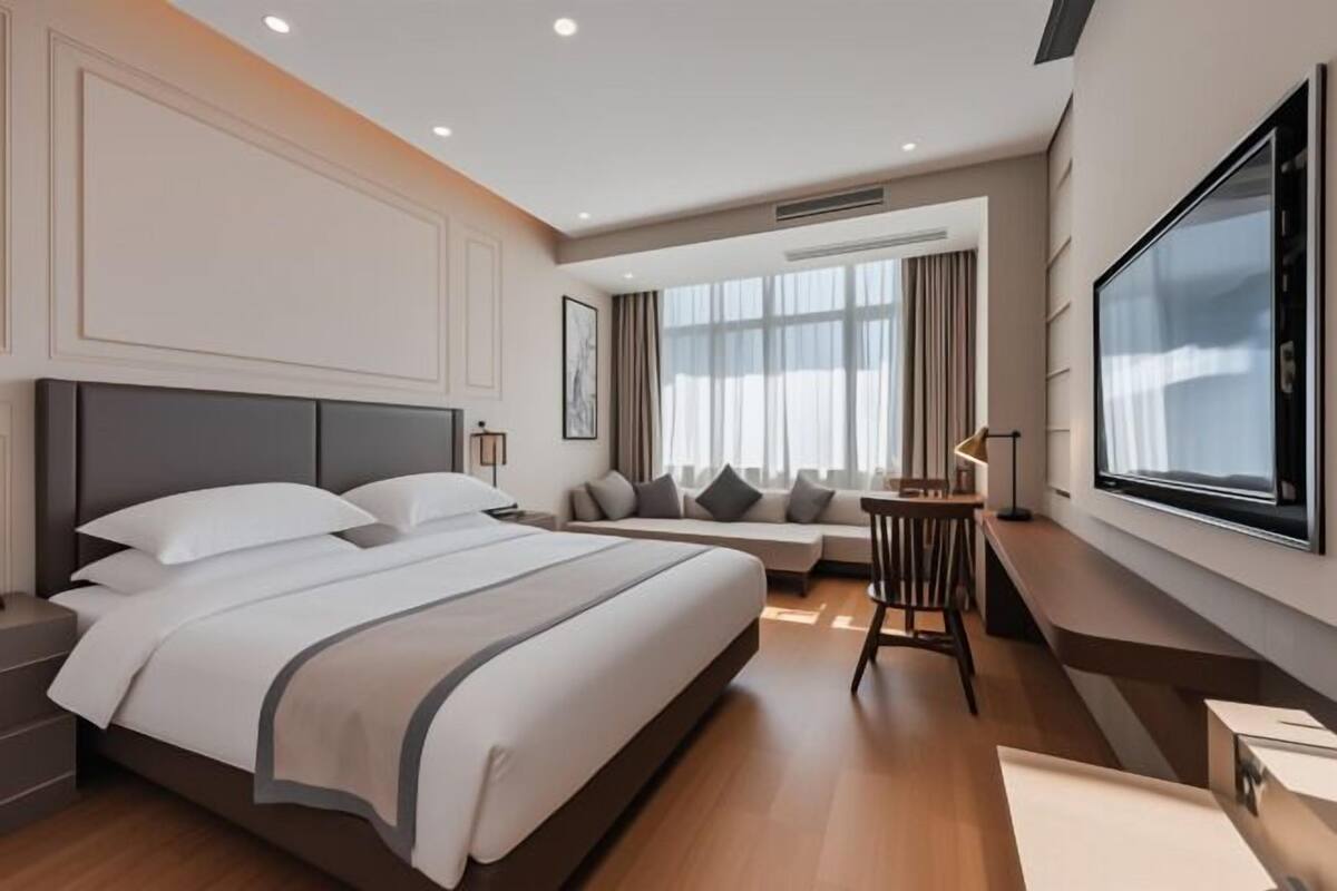 Una habitación de hotel moderna con una cama grande, un sofá, un televisor y un escritorio.