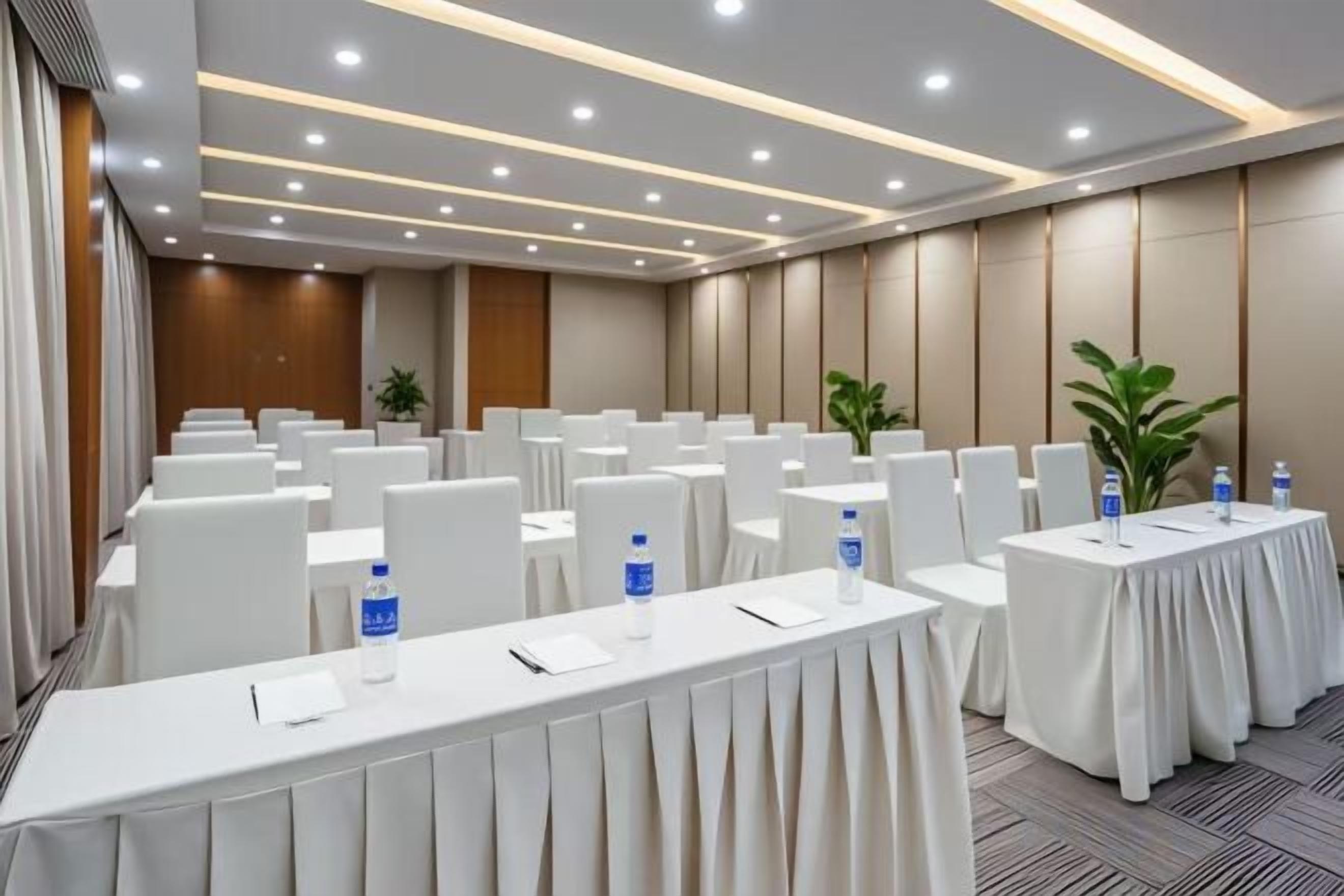 A conference room with rows of tables, chairs, and water bottles.