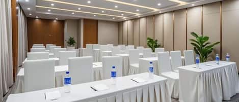 A conference room with rows of tables, chairs, and water bottles.