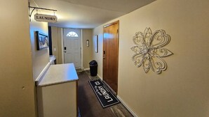 Un passadís amb un senyal de bugaderia, una porta, un safataire i una peça decorativa a la paret.