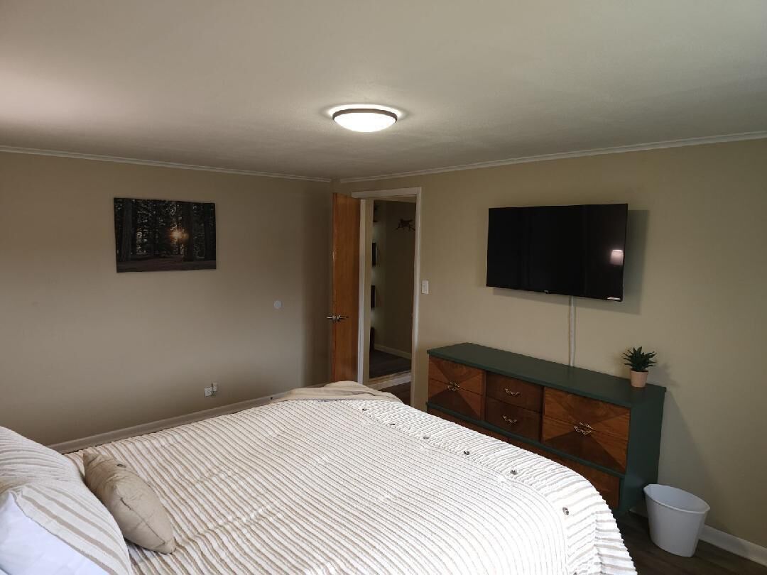 Een slaapkamer met een bed, een dressoir, een televisie en een kledingkast.