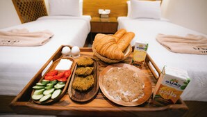 A breakfast tray with croissants, eggs, sliced cucumbers, and a plate of scrambled eggs on a wooden table in a hotel room. - MAKAI Pyramids Guest House (Giza)