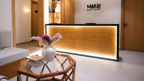 A reception area with a wooden reception desk, a glass coffee table, and a vase with flowers. - MAKAI Pyramids Guest House (Giza)