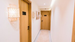 A hallway with wooden doors, light fixtures, and a herringbone-patterned floor. - MAKAI Pyramids Guest House (Giza)
