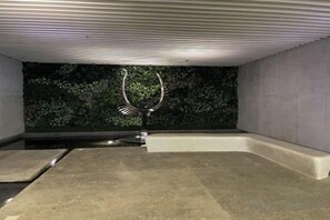 Een moderne badkamer met een betonnen vloer, een wandwastafel en een groene, begroeide wand.