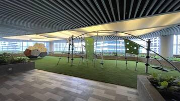 An indoor atrium with a green artificial turf, geometric sculptures, and a modern ceiling design.
