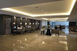 Een moderne hotelentree met een gepolijste vloer, zitgedeeltes en uitzicht over de stad.