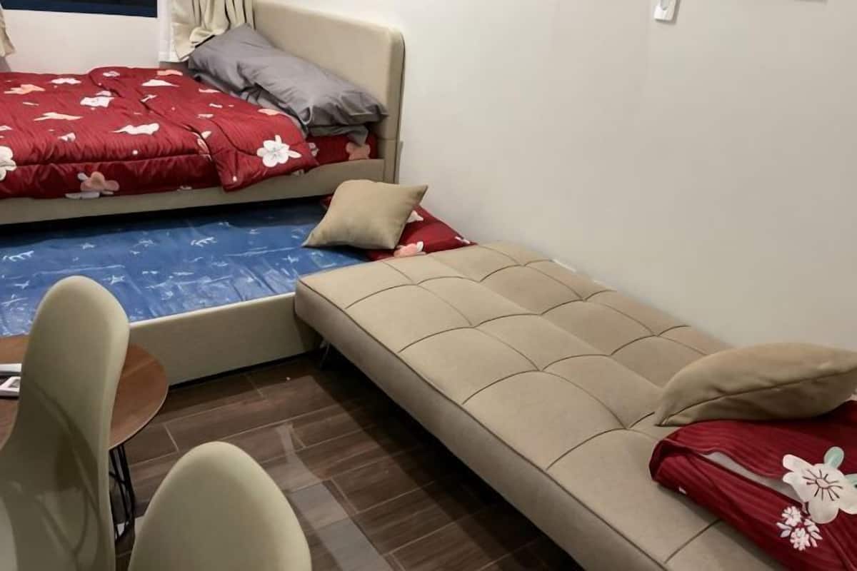 A room with a bed, a sofa, a chair, and a small table.