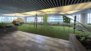 An indoor atrium with a green artificial turf area, a geometric sculpture, and a modern ceiling design. - Luxury Air Residences By Makati (Makati)