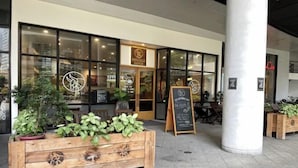 A restaurant with a wooden bench, potted plants, and a chalkboard menu outside. - Luxury Air Residences By Makati (Makati)