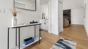 Ein modernes Wohnzimmer mit einem мраморный Konsolentisch, einem großen Spiegel und einem blauen Teppich mit Muster.