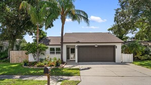 Ein Bungalow mit Garage, umgeben von einem gepflegten Rasen und Bäumen.