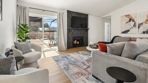 Ein modernes Wohnzimmer mit Kamin, einer Couch, einem Couchtisch und einem großen Fenster.