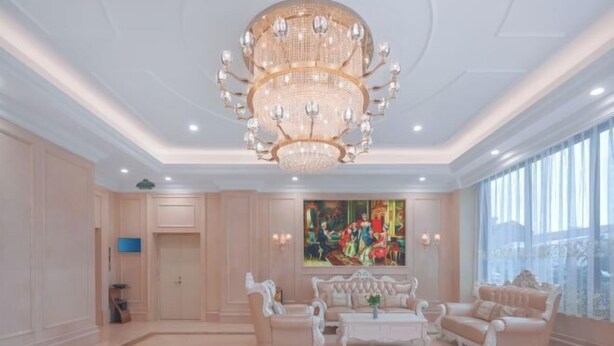 Een ruime woonkamer met een grote kroonluchter, elegant meubilair en een groot raam met uitzicht.