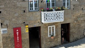 Un bâtiment en pierre doté de nombreuses fenêtres, d’un balcon orné de plantes en pot et d’une enseigne rouge indiquant qu’il s’agit d’un établissement où les animaux de compagnie sont les bienvenus.