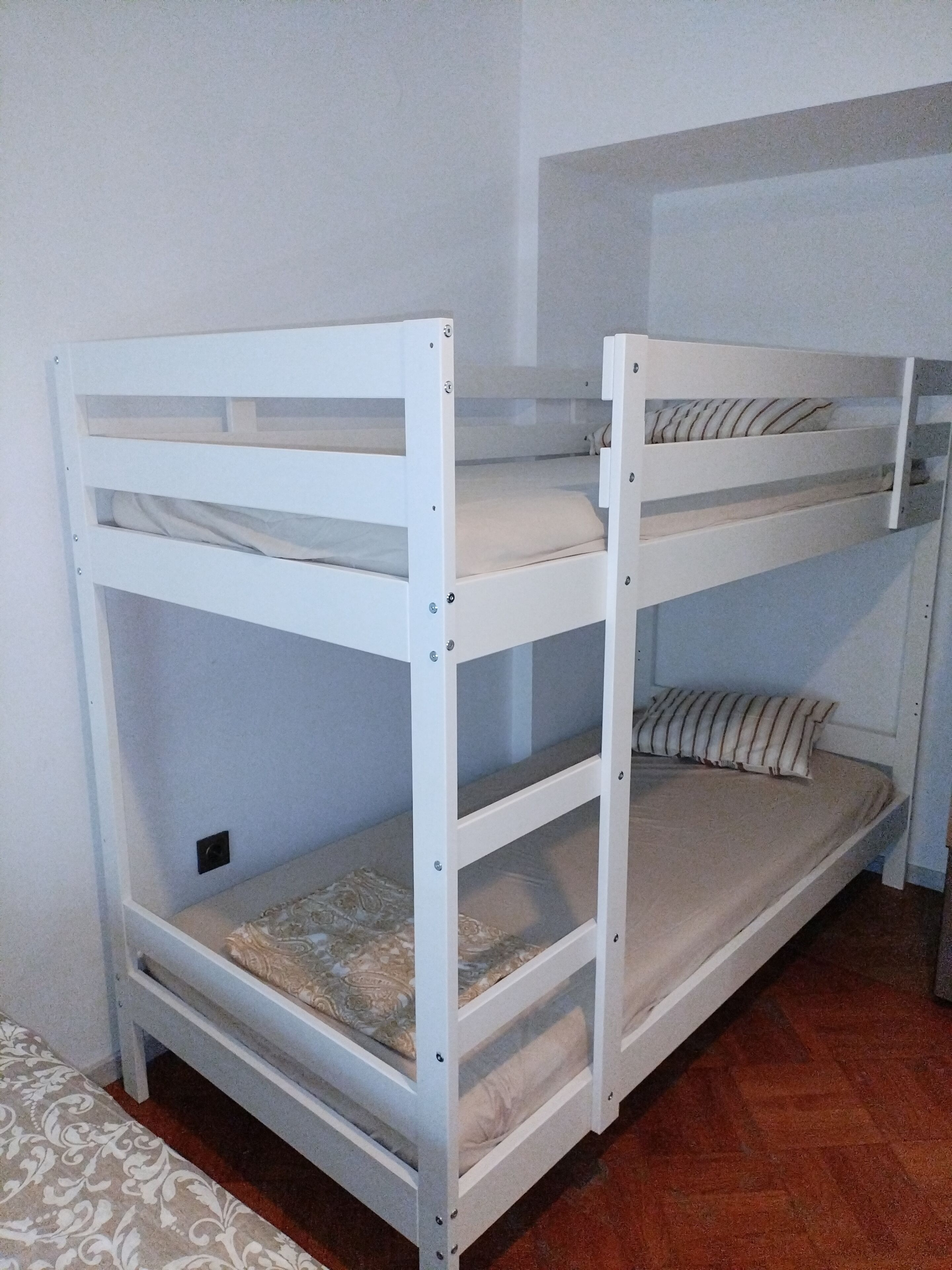 Un letto a castello con un letto inferiore e un materasso sul pavimento.