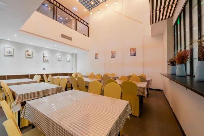 A dining area with multiple tables and chairs, a mezzanine level, and artwork on the walls.