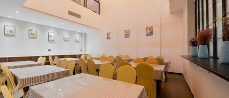 A dining area with multiple tables and chairs, a mezzanine level, and artwork on the walls.
