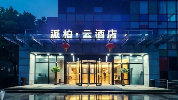 A hotel entrance with a glass facade, a revolving door, and a sign above the entrance.