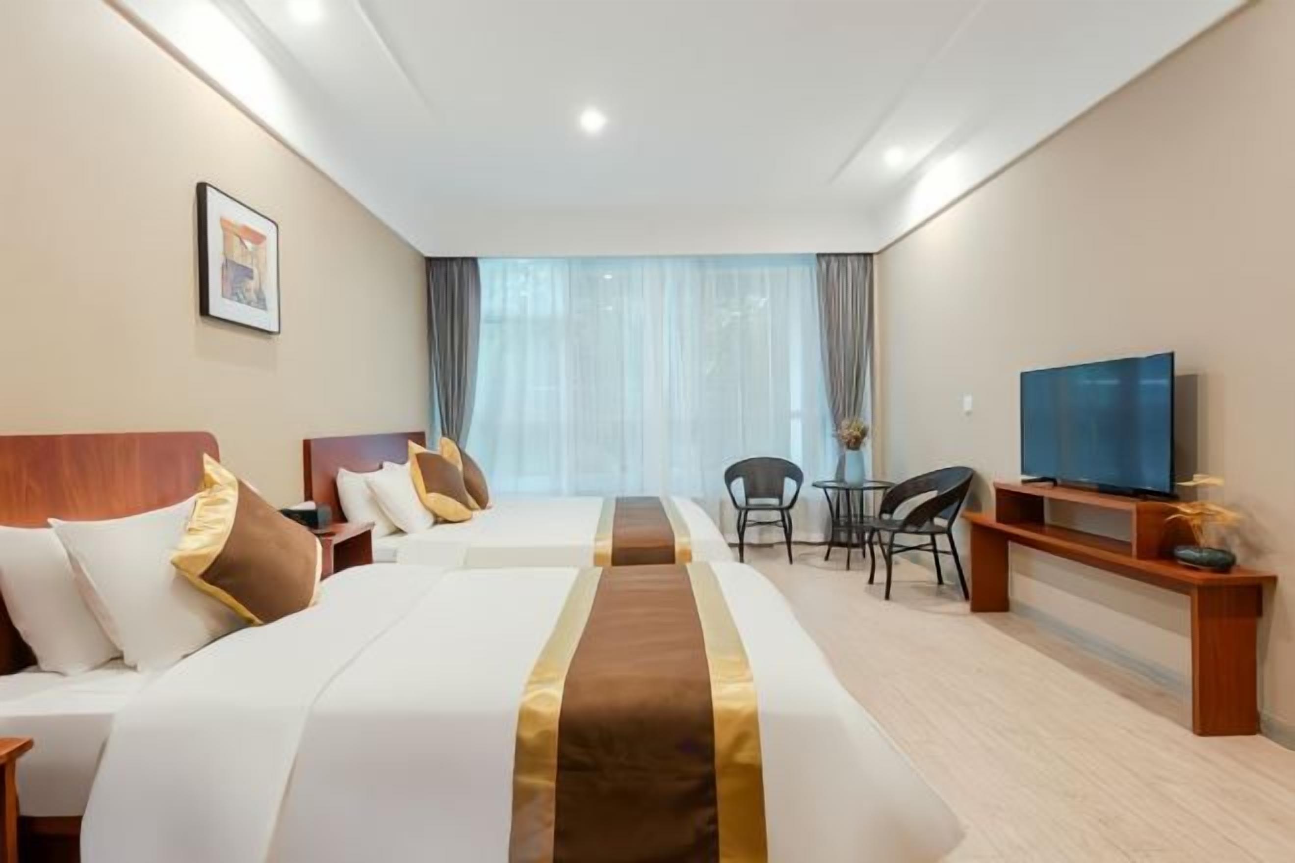 Ein Hotelzimmer mit einem großen Bett, einem Fernseher, einem Schreibtisch und einem Sessel.