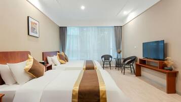 Ein Hotelzimmer mit einem großen Bett, einem Fernseher, einem Schreibtisch und einem Sessel.