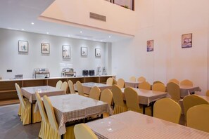 A dining area with multiple tables and chairs, a counter with a coffee machine, and framed pictures on the walls.
