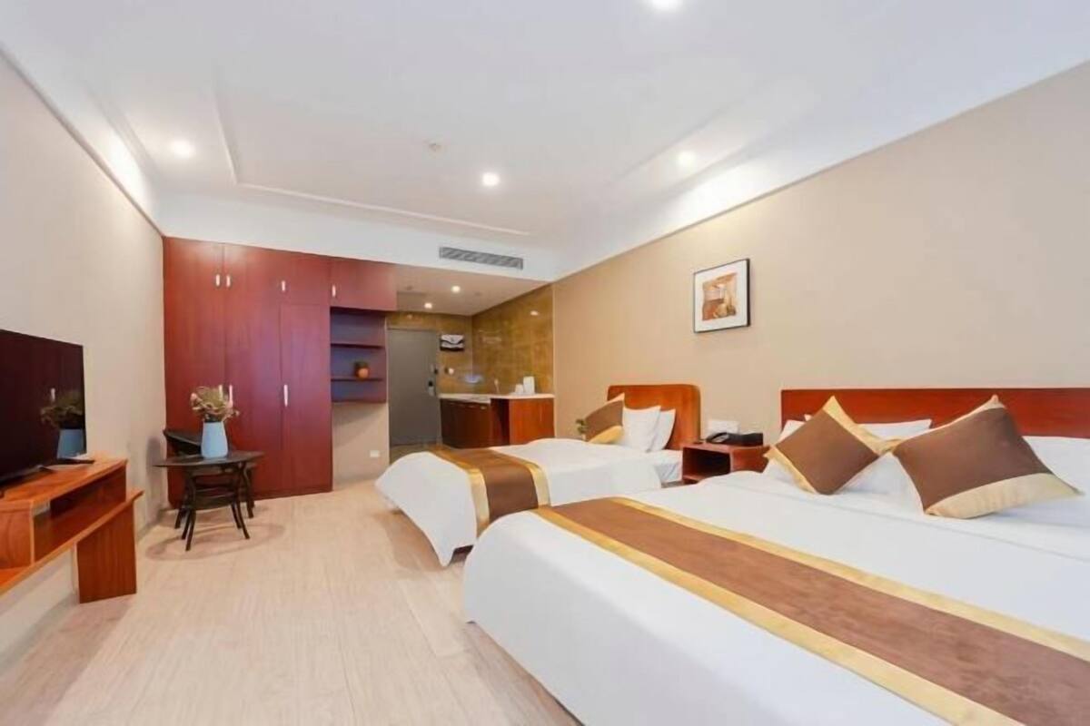 Une chambre d’hôtel avec deux lits, une télévision, un bureau et une armoire.