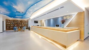A modern reception area with a curved reception desk, a bookshelf, and a seating area with chairs.