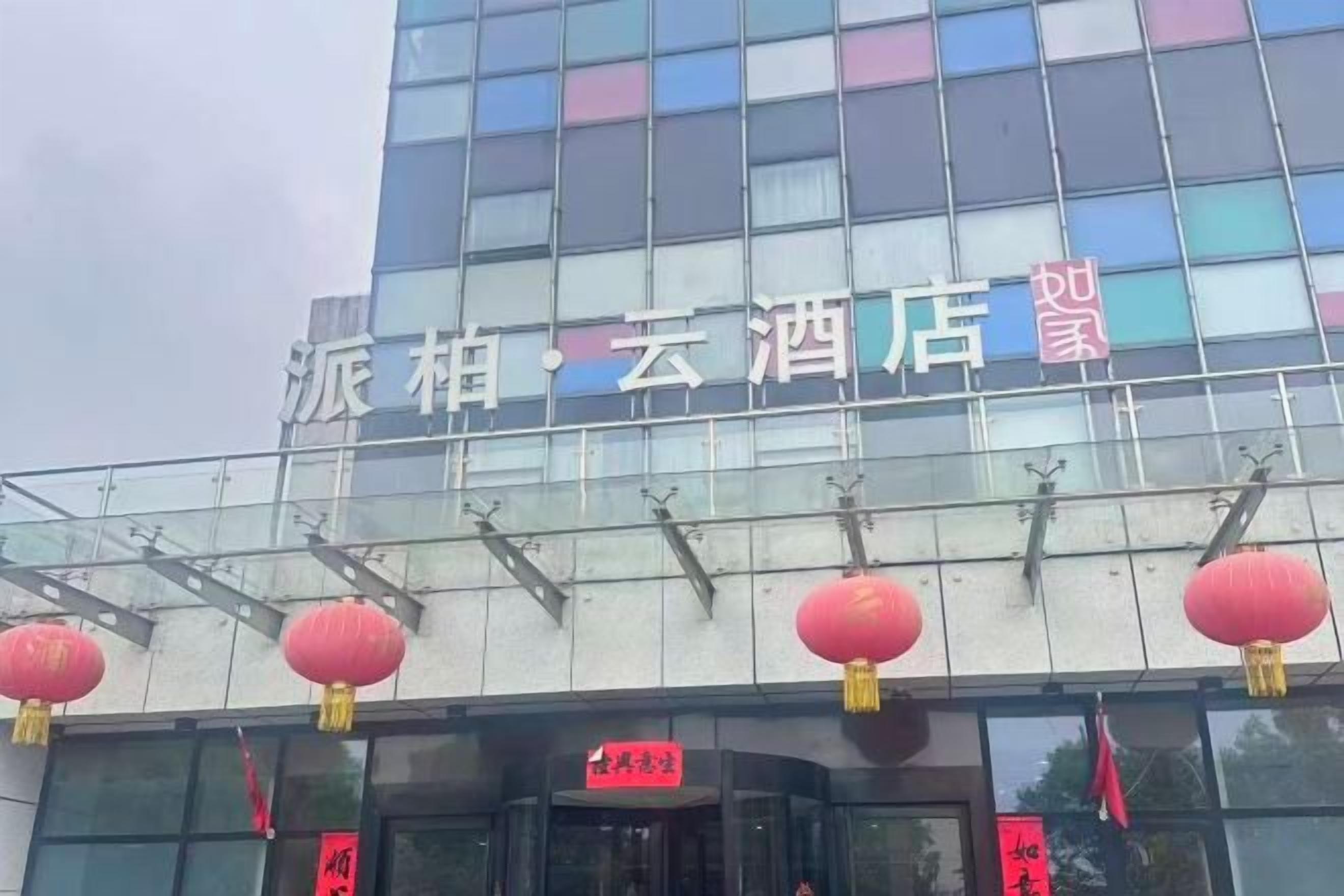 A hotel with a modern glass facade and red lanterns.