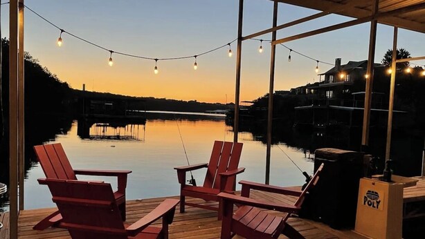Une terrasse en bois avec des chaises Adirondack rouges et un espace barbecue.
