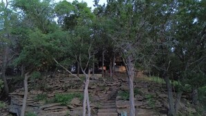 Un escalier en pierre menant vers le haut d’une pente rocheuse, le tout étant entouré d’arbres.
