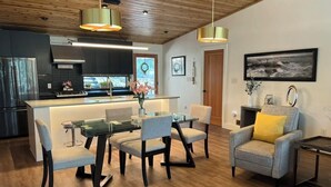 Une cuisine moderne dotée d’un îlot central, d’un coin repas avec des chaises et d’un espace de vie comprenant un canapé et une table d’appoint.