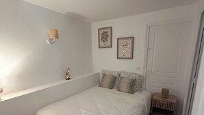Un dormitorio con cama, mesita de noche y estante en la pared.