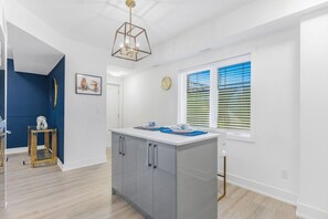 Enjoy cooking in the central kitchen with a white countertop and grey cabinets, illuminated by a unique pendant light.