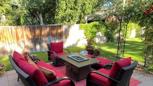 Un patio al aire libre con mobiliario de mimbre, una mesa y una planta en maceta.