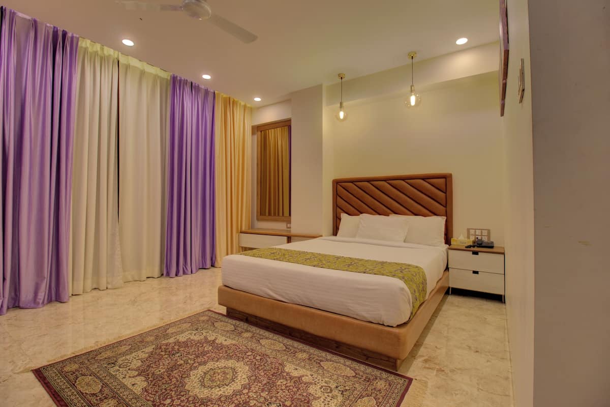 Une chambre à coucher avec un lit, une table de chevet, des rideaux et un ventilateur de plafond.