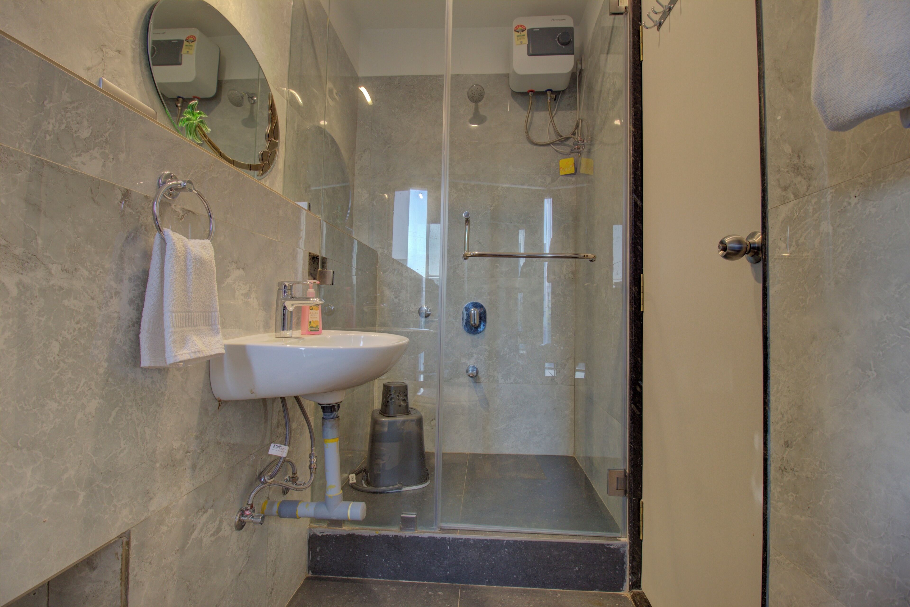 Un baño moderno con ducha de vidrio, un lavamanos con espejo y un aro para toallas en la pared.