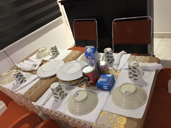 Une table à manger dressée avec des assiettes, des tasses et une canette de soda.