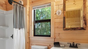 Ein Badezimmer einer Holzhütte mit Toilette, Waschbecken und Dusche.