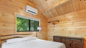Ein Schlafzimmer einer Holzhütte mit einem Bett, einem Fenster und einem Schrank.