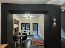 Un comedor moderno con una pared de acento de piedra, una araña y vistas a través de un ventanal.