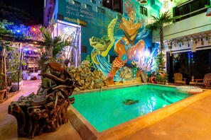 A pool area with a mural, wooden seating, and potted plants. - La Casa de Jardin (Isla Mujeres)