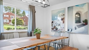 A dining area with a long wooden table, metal chairs, and a potted plant. - Modern and Spacious House (Pittsburgh)