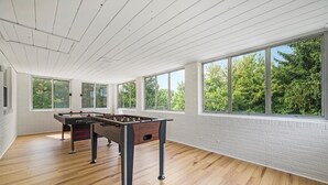 A spacious room with a foosball table, large windows, and wooden flooring. - Modern and Spacious House (Pittsburgh)