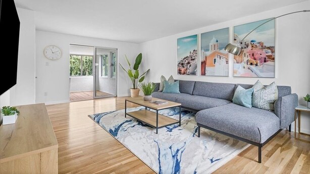 A modern living room with a grey sofa, wooden coffee table, and a large window. - Modern and Spacious House (Pittsburgh)